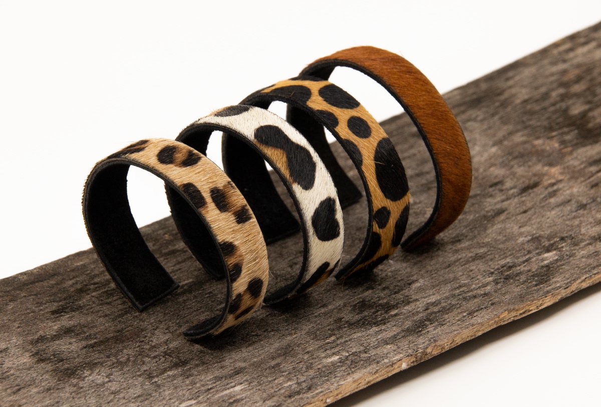 Série de bracelets à motifs léopard et vache disposés sur un support en bois - Chiche communication
