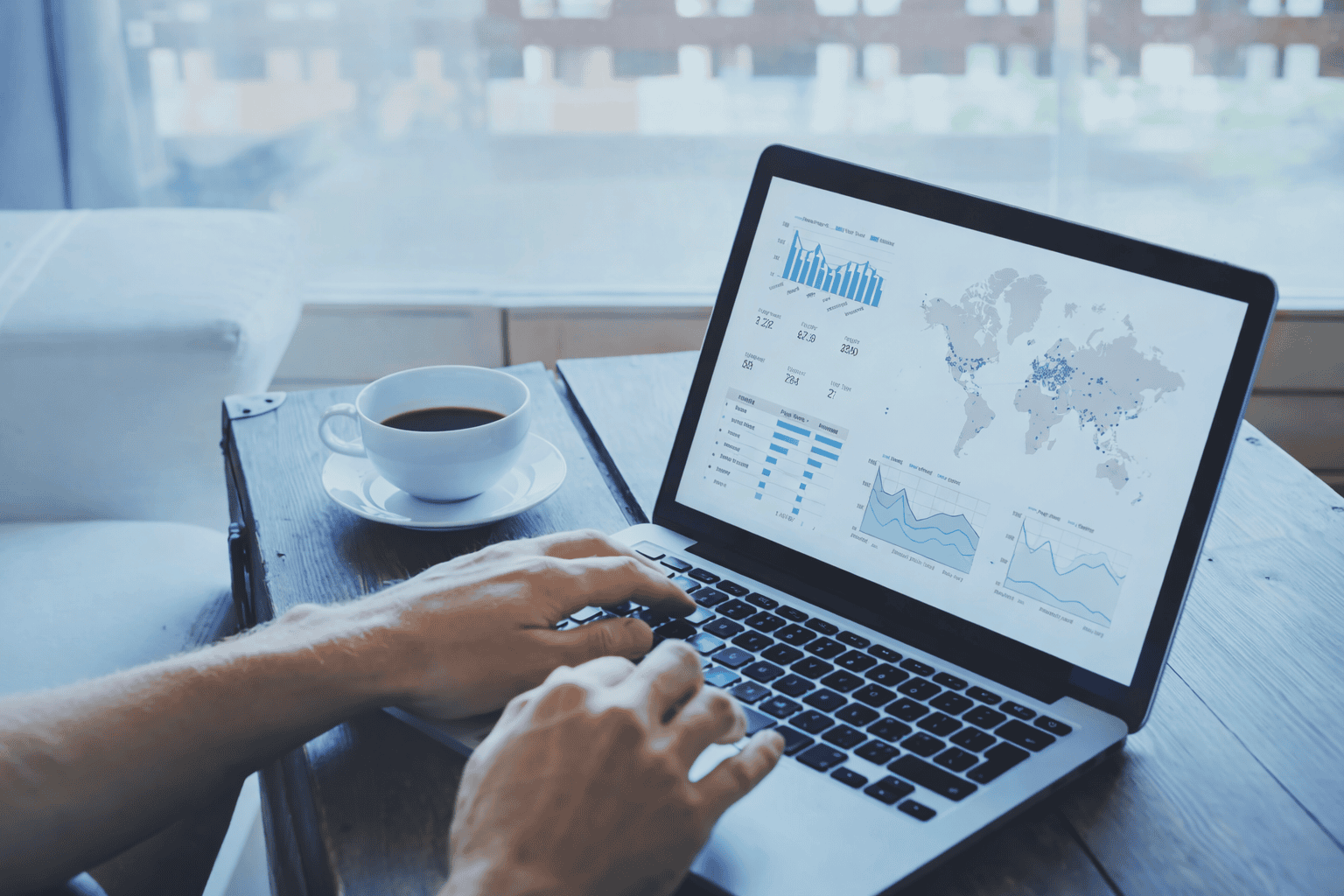 Analyse de données sur ordinateur portable avec graphiques et carte mondiale, dans un espace de travail avec café
