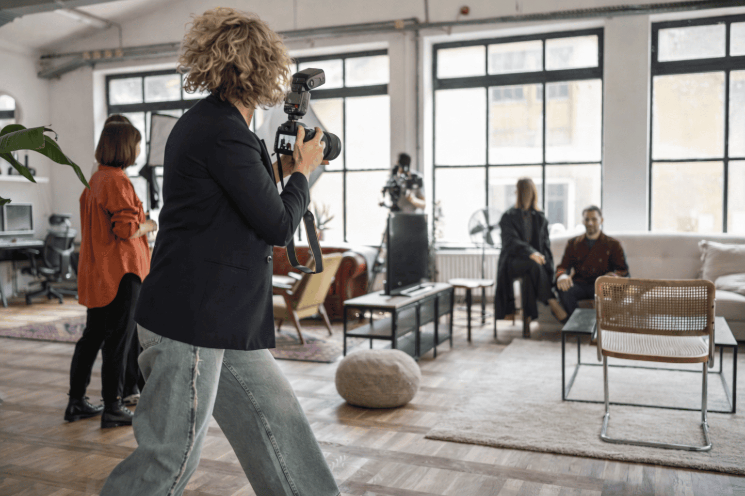 Photographe en séance photo dans un loft lumineux, capturant des portraits avec équipe de production et matériel audiovisuel