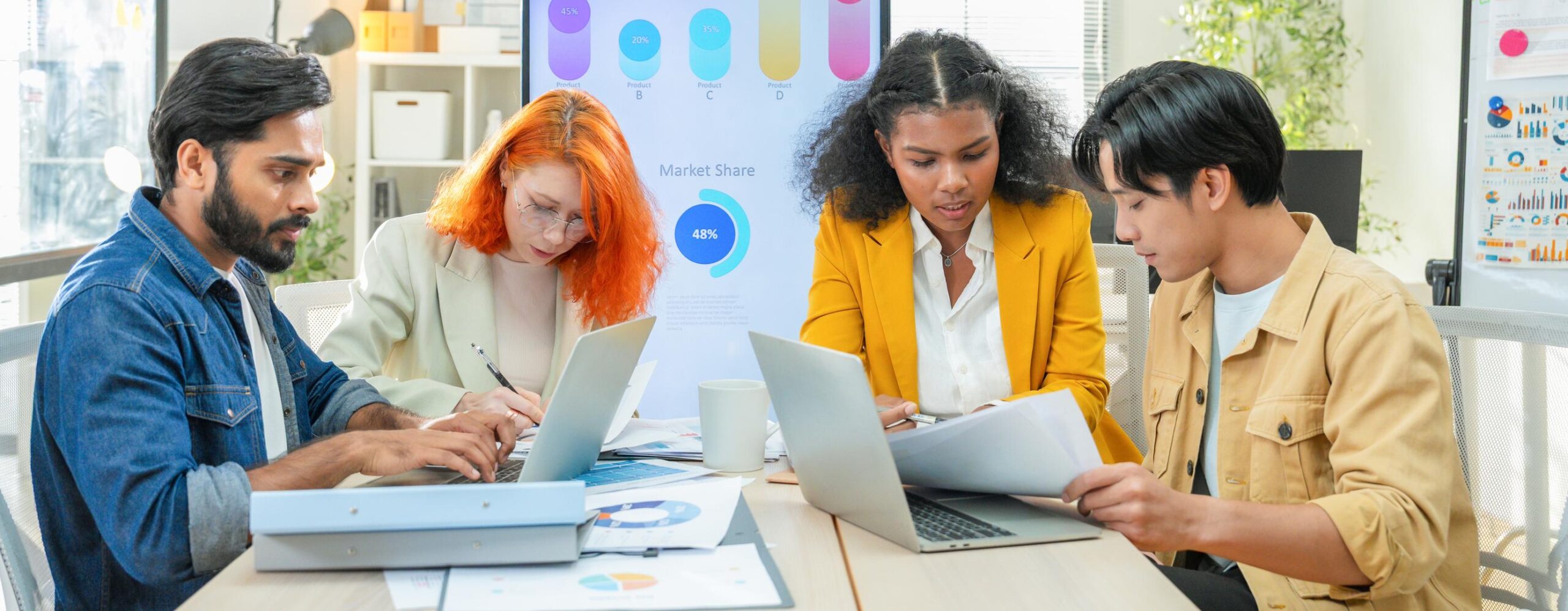 Équipe analysant des données et collaborant autour d’ordinateurs avec graphiques en arrière-plan, illustrant l’optimisation continue et l’amélioration des performances basée sur les données