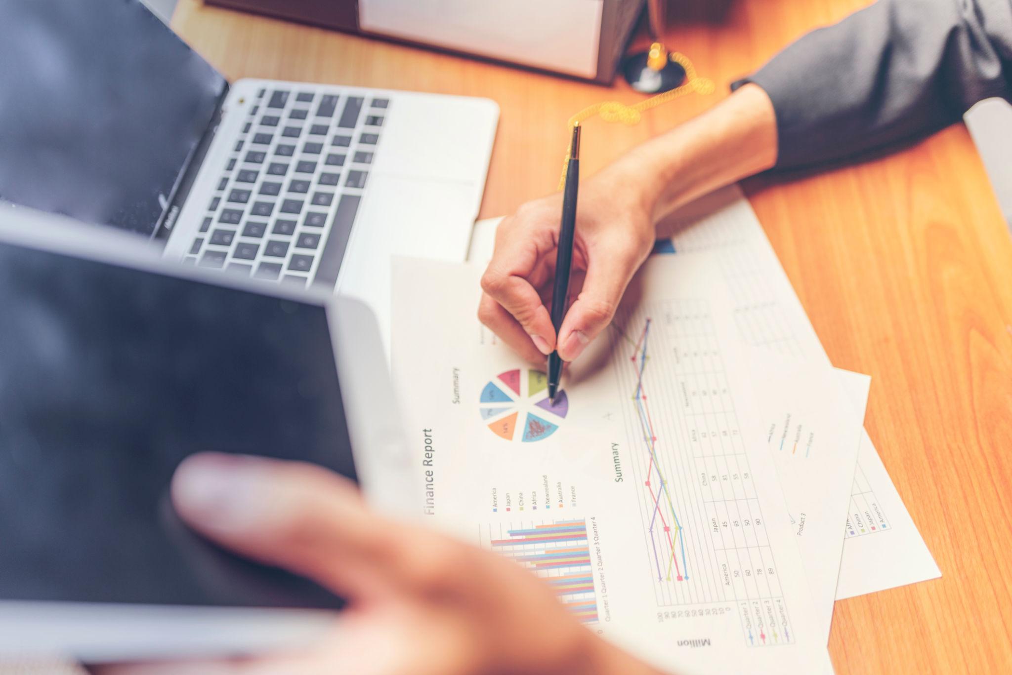 Personne analysant un rapport personnalisé avec graphiques et indicateurs sur un bureau, illustrant la lecture et l’interprétation de données adaptées à l’activité